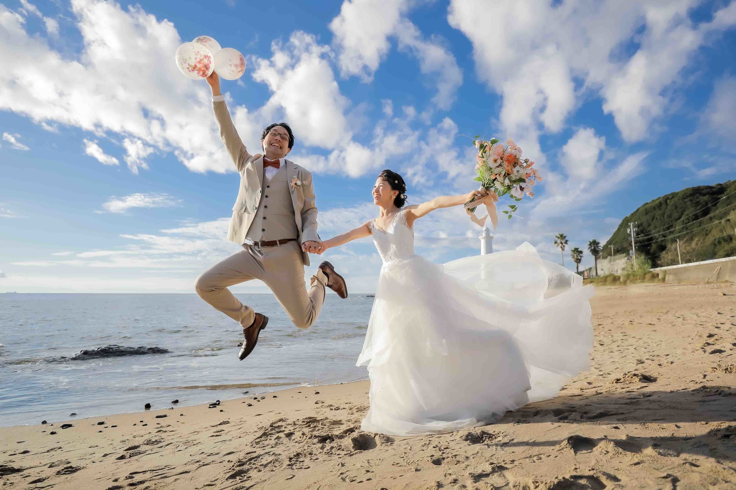 alt="野間灯台でビーチ前撮りをする笑顔の新郎新婦"