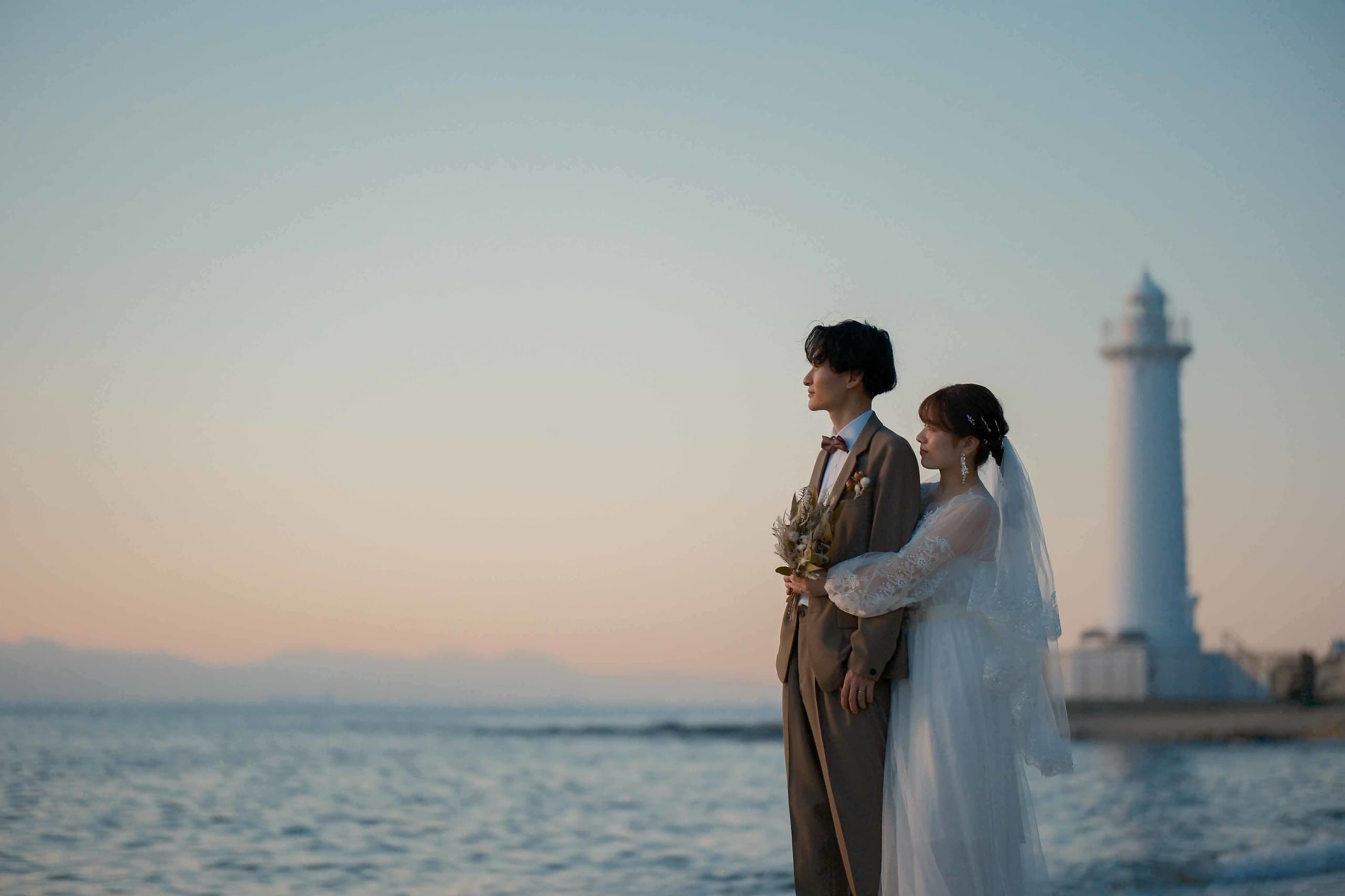 alt="野間灯台でビーチ前撮りをする笑顔の新郎新婦"