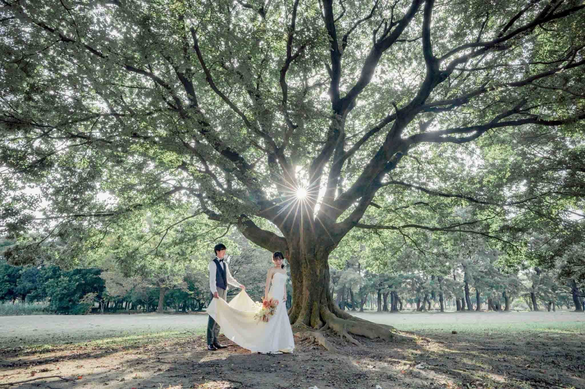 alt="庄内緑地公園でドレス前撮りをする笑顔の新郎新婦"