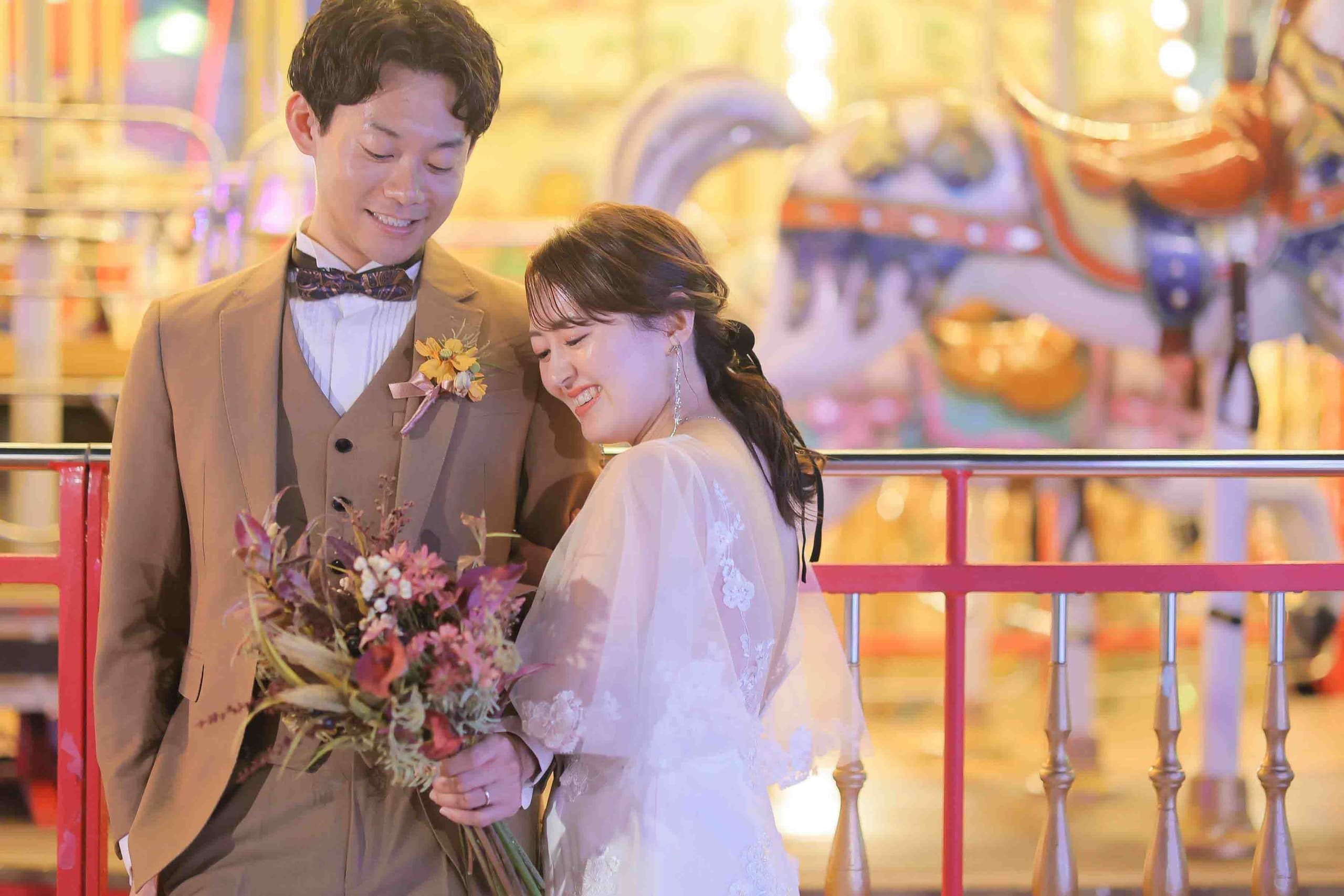 alt="夜の遊園地でナイトドレス前撮りをする笑顔の新郎新婦"