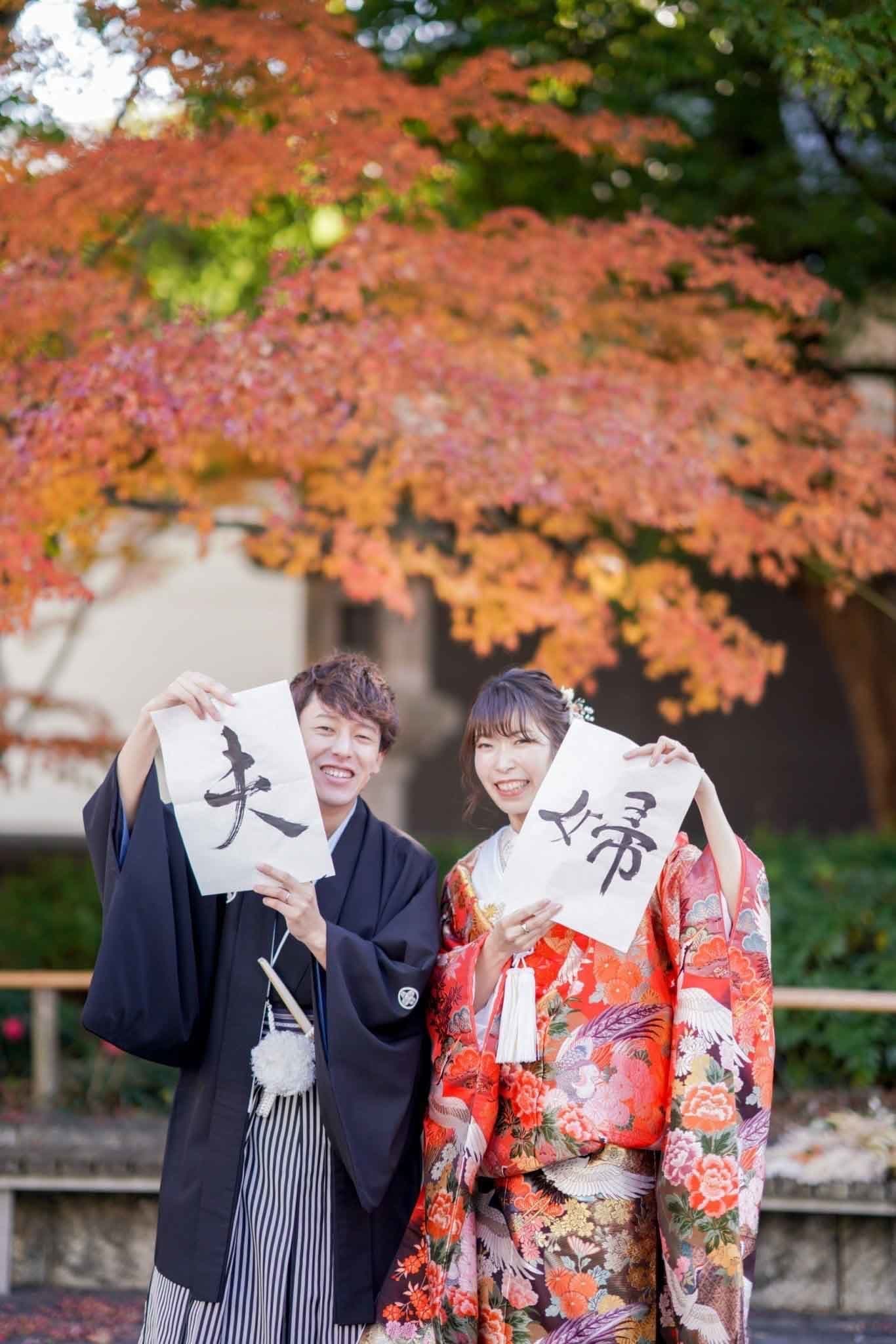 紅葉の徳川園前撮りで笑顔で習字を持つ新郎新婦