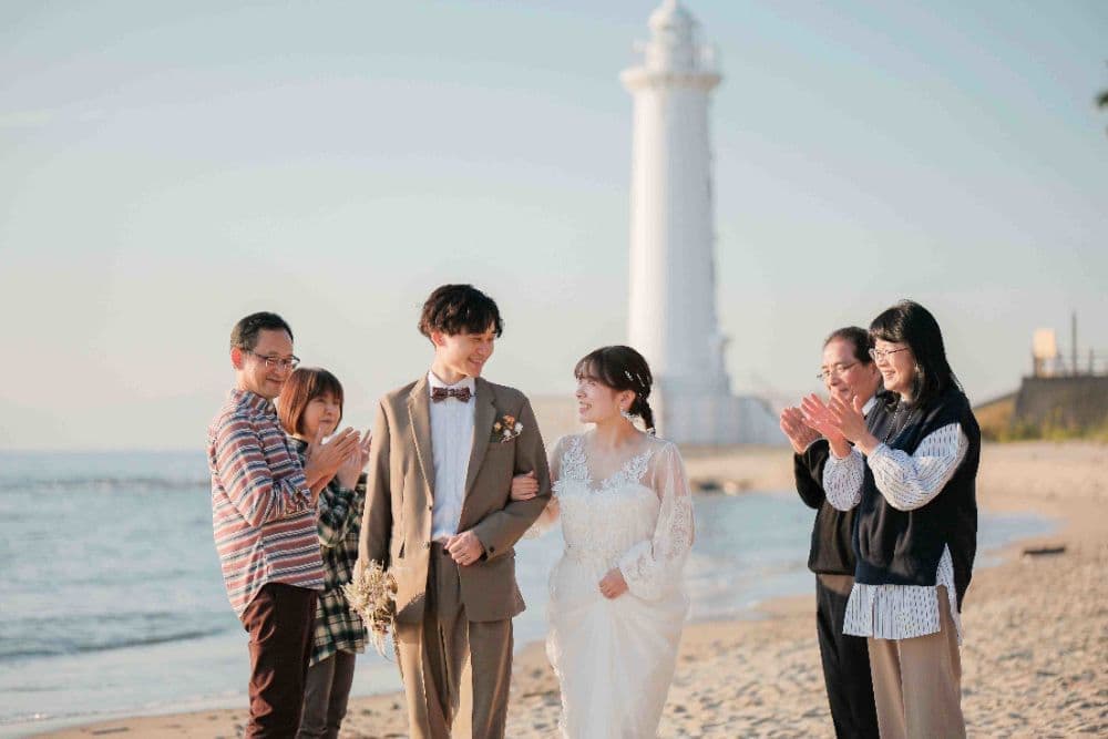 野間灯台前撮りで家族と写真を撮る新郎新婦